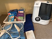 Photo showing Honeywell humidifier, electric blanket, and basket with various medical supplies including gloves and bandages.