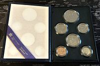 Opened black presentation box showing six Canadian coins in protective capsules on the right side and the left side with white fabric and purple ribbon labeled 'Specimen Condition Canada 1985'.