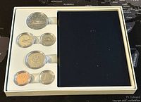 Top view of the 1986 Canadian specimen coin set case with six coins arranged inside. Coins vary in size and metal color, placed in fitted slots in a cream and dark blue display case.