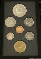Photo of front face of set showing seven coins in black foam tray with detailed Canadian images on reverse sides.
