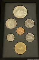 Top view of the coin set in black holder showing front designs of the coins including a large silver dollar with canoe and other coins