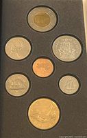 Top side of the 7 coin set showing front side of coins including Polar Bear Twoonie, Loonie with Flying Loon, Fifty Cent Coat of Arms, 25 Cent Caribou, 10 Cent Bluenose sailboat, 5 Cent Beaver, and 1 Cent Maple Leaf.