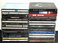Photo showing 30 assorted rock music CDs in jewel cases stacked vertically and horizontally.