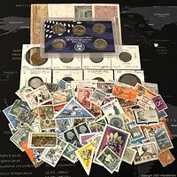 Layout showing coins in holders, US Mint proof set and a pile of diverse stamps with various colors and themes