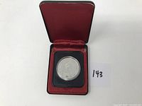 Obverse side of the 1977 Canada Silver Dollar showing Queen Elizabeth II in protective capsule within red velvet-lined display case.