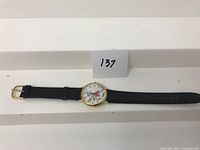 Full view of the watch laid out horizontally showing gold-tone case, black leather strap, and Roger Rabbit dial with character's arms serving as watch hands.