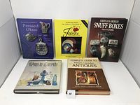 Five collector books on various topics including pressed glass, Fiesta collectibles, snuff boxes, glass in Canada, and French-Canadian antiques arranged upright and stacked.