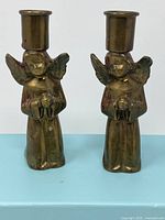 Front view of the two angel-shaped solid brass candlestick holders