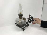 Oil lamp mounted in cast metal swivel wall bracket, showing overall condition and detail.