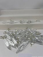 Clear crystal chandelier prisms piled together showing the faceted design, ball tops, and hooks.