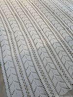 Close-up photo of the hand crocheted tablecloth showing detailed lace crochet pattern in off-white color.
