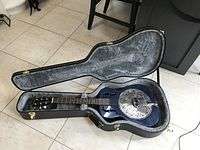 Blue resonator guitar seated in open gray-velvet lined hardshell case