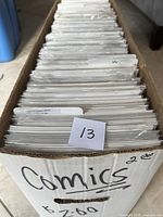 Photo showing the top view of a large box filled with comics in plastic sleeves with backboards, labeled 'Comics' and some numbering.