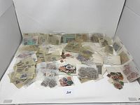 Large collection of circulated worldwide postage stamps arranged in groups inside plastic sleeves and envelopes, many labeled by country or region.