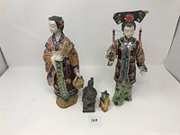 Front view of all four oriental figurines, two large porcelain and two smaller ceramic figures