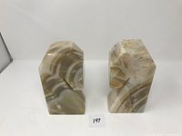 Front view showing the two marble bookends standing upright, displaying their natural striation patterns in beige and cream tones.