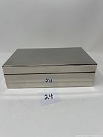 Closed rectangular silver plate box with smooth minimalist design, shown from front angle.