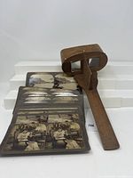 Wooden stereoscope viewer with 21 stereoscopic cards spread out in front showing paired black and white images.