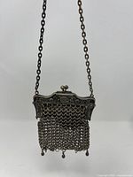 Front view of the chain-link coin purse showing the ornate metal frame and hanging chain-link mesh body with the chain strap visible.