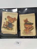 Two vintage animal transfer decals on black background, one of a teddy bear playing with a ball and another of a fox holding a toy horn.