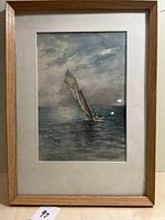 Front view of framed watercolour depicting a lone sailboat on the ocean under cloudy sky.