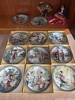 Eleven boxed collector plates arranged in grid