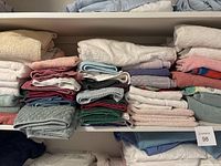 Multiple stacks of bathroom towels folded on shelves in assorted colors and sizes