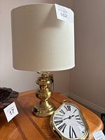 Brass lamp with cream shade and Dali-inspired clock on wood table.