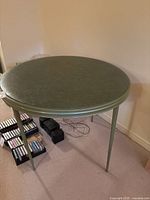 Four-legged green round card table showing top and legs