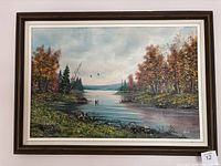 Full view of the framed landscape oil painting showing the autumn scenery with river, trees, and birds.