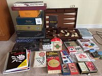 Photo showing entire lot with stacked game boxes including Scrabble, Mastermind, Trivial Pursuit, and others, along with game boards, playing pieces, cards, and game books.