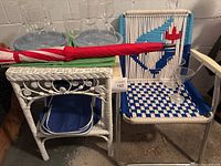 Photo showing vintage Blue Jays crochet lawn chair with woven seat and backrest, white wicker side table holding placemats and umbrella, plastic glasses on top and basket underneath.