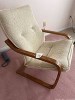 Front-right angle showing curved wooden frame and tufted cushion