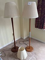 Two floor lamps with shades and one separate shade on floor