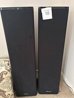 Front view of the pair of tall Mirage floor-standing speakers with black fabric covers.
