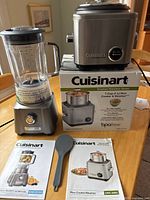 Full view of the Cuisinart Velocity blender and 7-cup rice cooker on its original box with instruction manuals and a grey rice paddle in front.