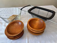 Full set displayed showing glass bowl, wooden bowls stacked in two piles, and over-the-sink colander resting behind them.