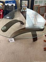 Angled front view showing overall triangular glass top and three curved wood legs