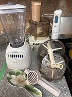 Osterizer blender, Cuisinart food processor, Braun hand blender, floral spoon rest and kitchen tool on counter