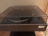 Sony PS-1100 turntable system with dust cover closed, showing wood base and front label.