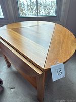 Round teak top with hinged triangular leaf partially open
