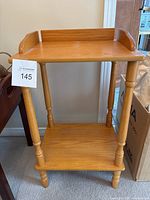 Front view of woodlike side table with two shelves and turned legs