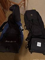 Two golf travel bags side by side, one Top-Flite brand and one Alien brand with wheels and handle visible.