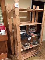 Front view of two wooden utility shelves with various tools on one shelf.