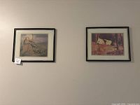 Both framed pictures side-by-side on a white wall, showing overall condition and frame style.