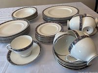 Photo showing the full set including stacked plates, teacups and saucers on a table.
