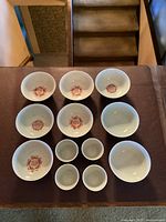 Top-down view of all 12 pieces laid out, showing red center symbols in six bowls and two plain bowls