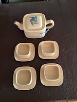 Overhead view of teapot and four cups with saucers on dark surface