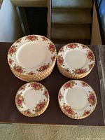 Top view of the arranged plates in four stacks showing different sizes and floral design with gold trim