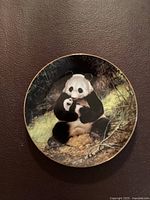 Front view of the collectible panda plate showing the detailed illustration of a panda and her cub in a natural setting with a gold rim.